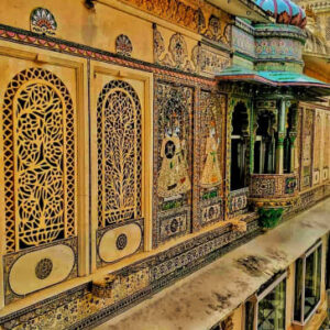 Ornate wall carvings, paintings, and a colorful domed balcony at the City Palace in Udaipur, Rajasthan.