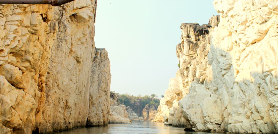A serene river flows through towering white marble cliffs in Bhedaghat, Jabalpur.